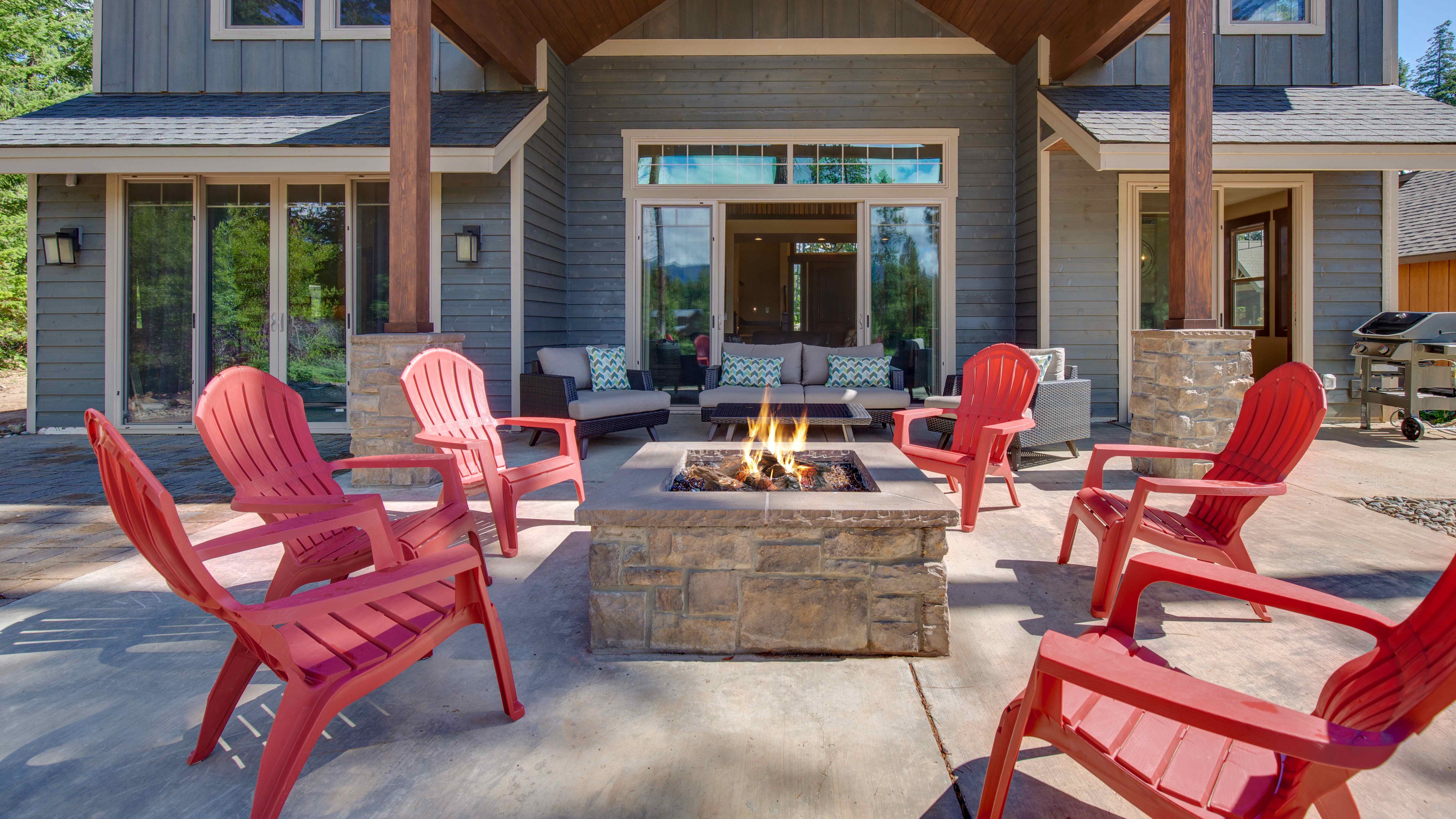 Red patio chairs placed around a stone fire pit 