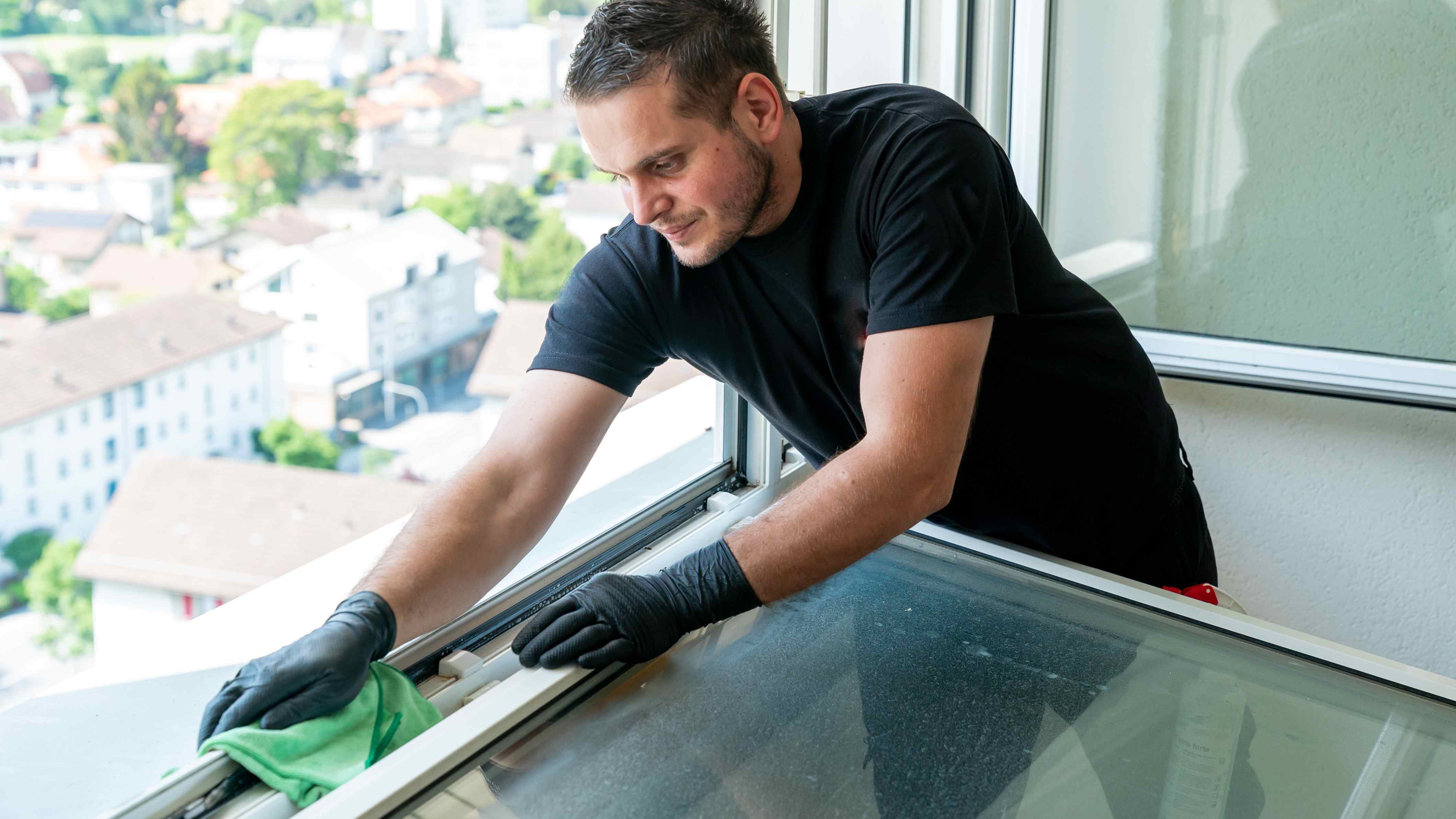 Man using a microfiber cloth to clean a tilt-in-window 