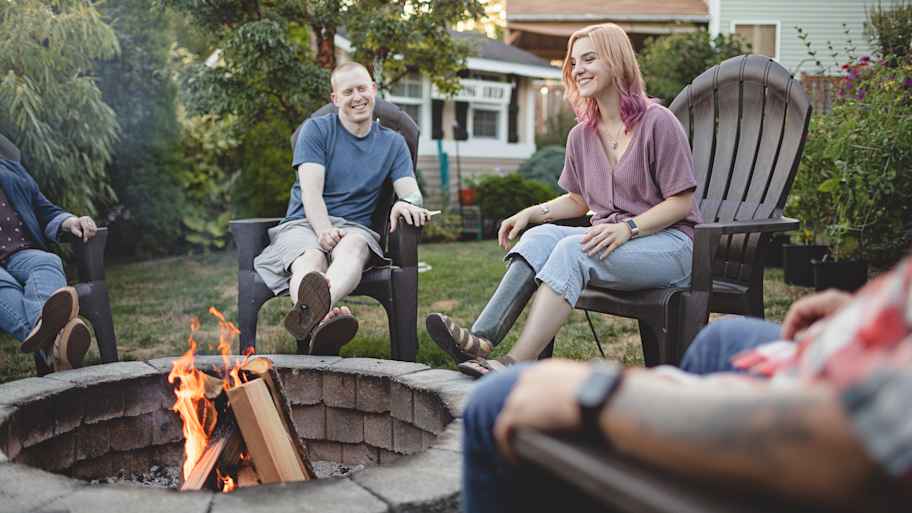Family sitting around a stone fire pit in the yard 