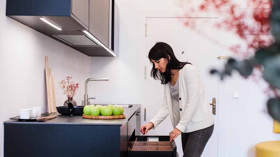 A woman opening a kitchen drawer
