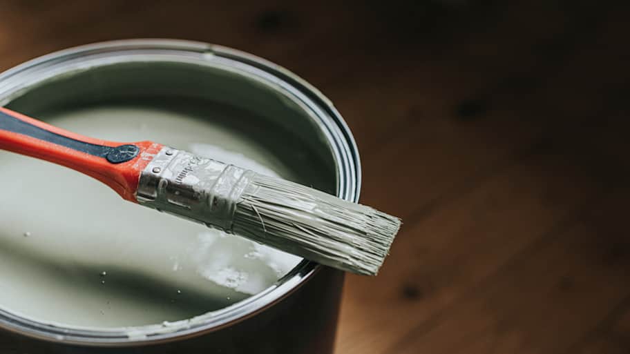 A small paintbrush sits on top of tin of light green