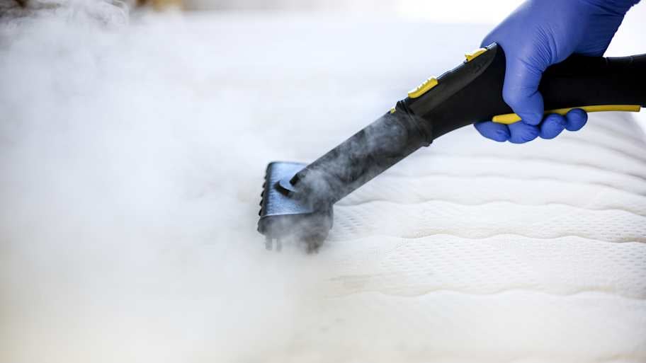 Person using a steamer to clean a mattress