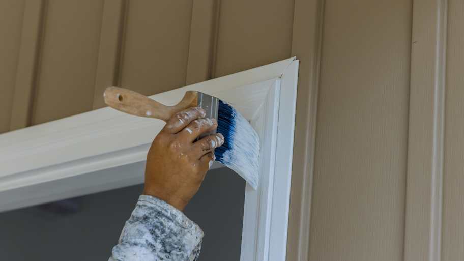 Man painting wooden door trim