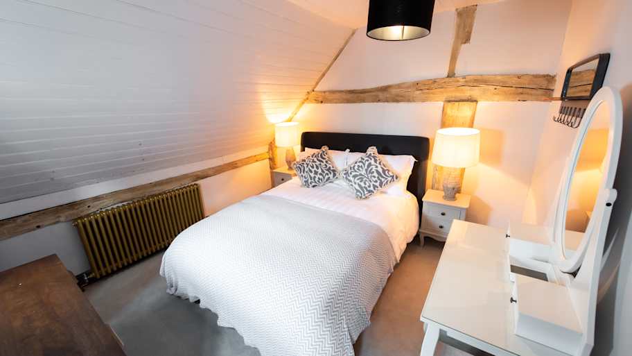 A small bedroom with exposed beams above the bed