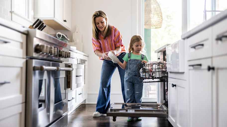 Mother and daughter loading dishwasher