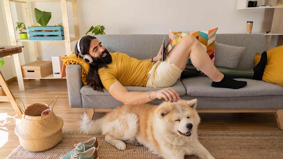 Man sitting on the couch and petting his dog  