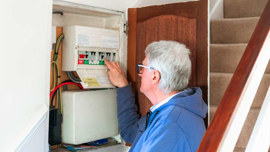 man looking at electrical panel in cabinet