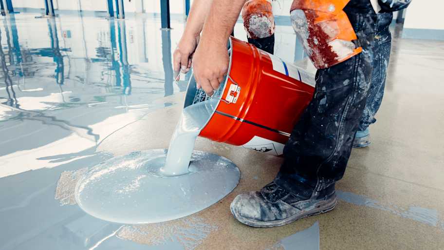 Contractor pouring epoxy resin on a concrete floor 