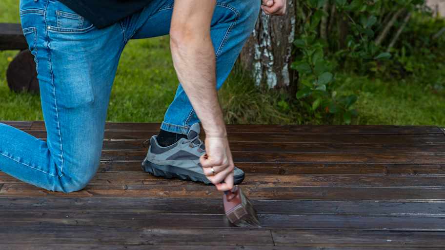 Person applying stain to a wooden deck