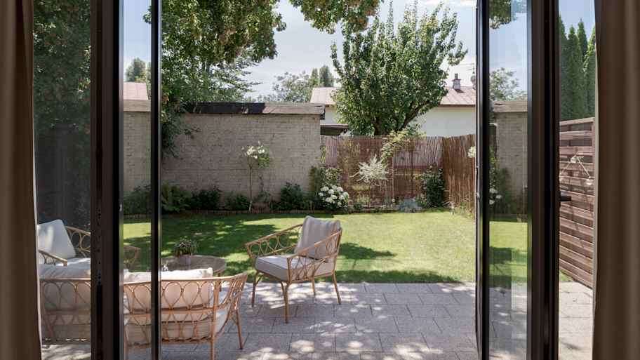 View from open balcony window to rattan furniture in small but cozy garden