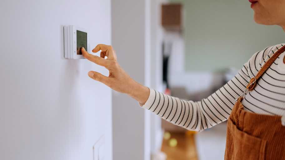 woman adjusting wall thermostat