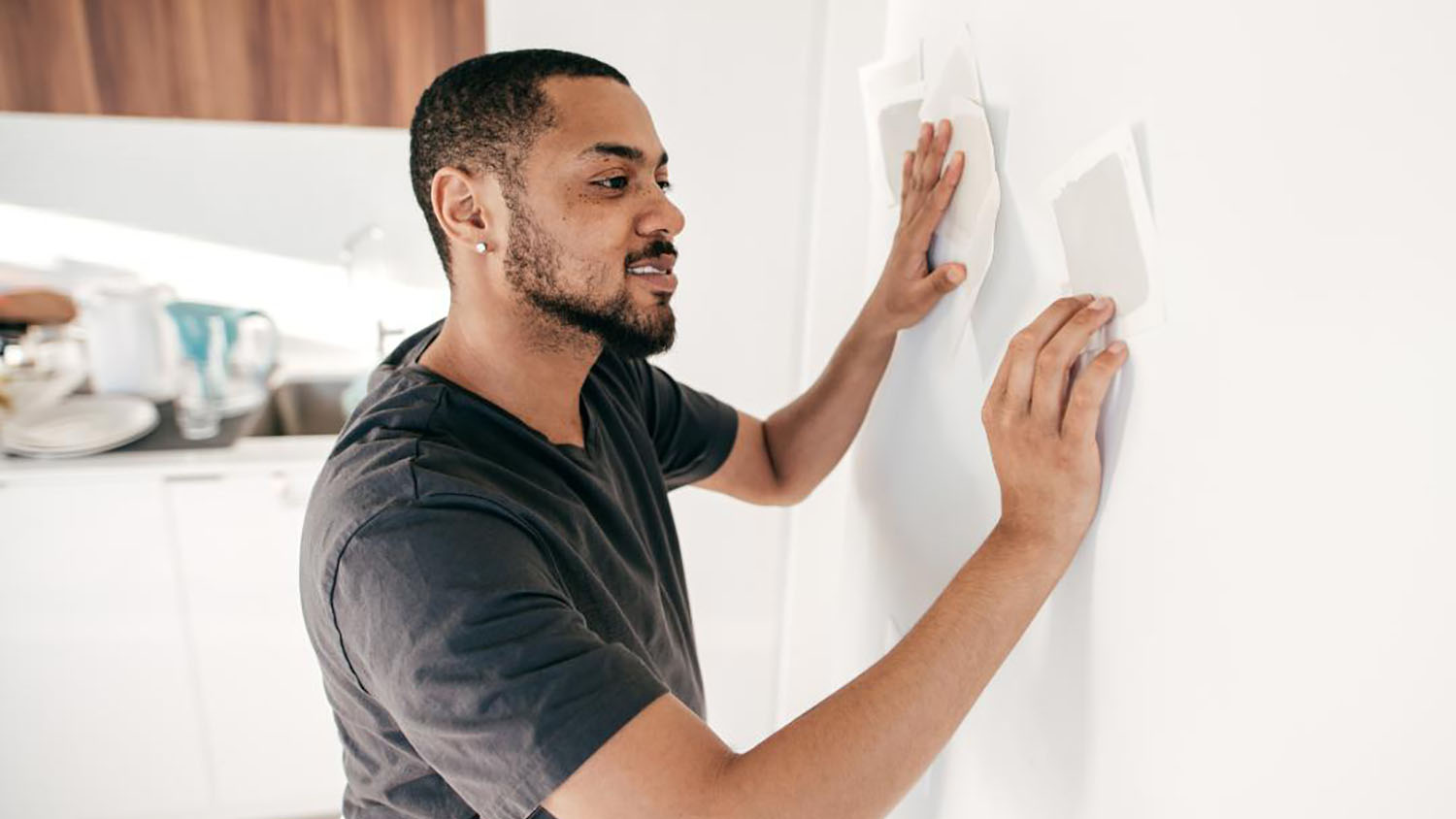 Person holding paint color cards up to wall