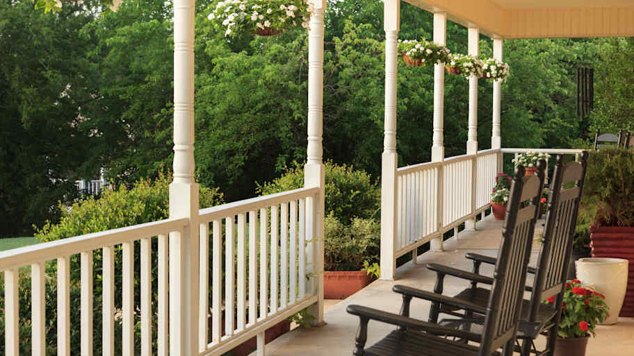 A porch with two rocking chairs and hanging pots