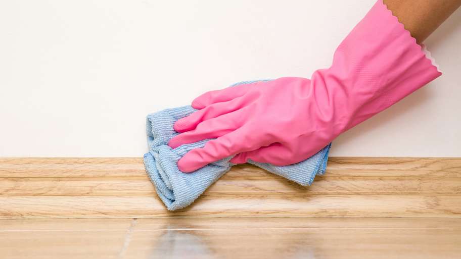 A person cleaning a baseboard
