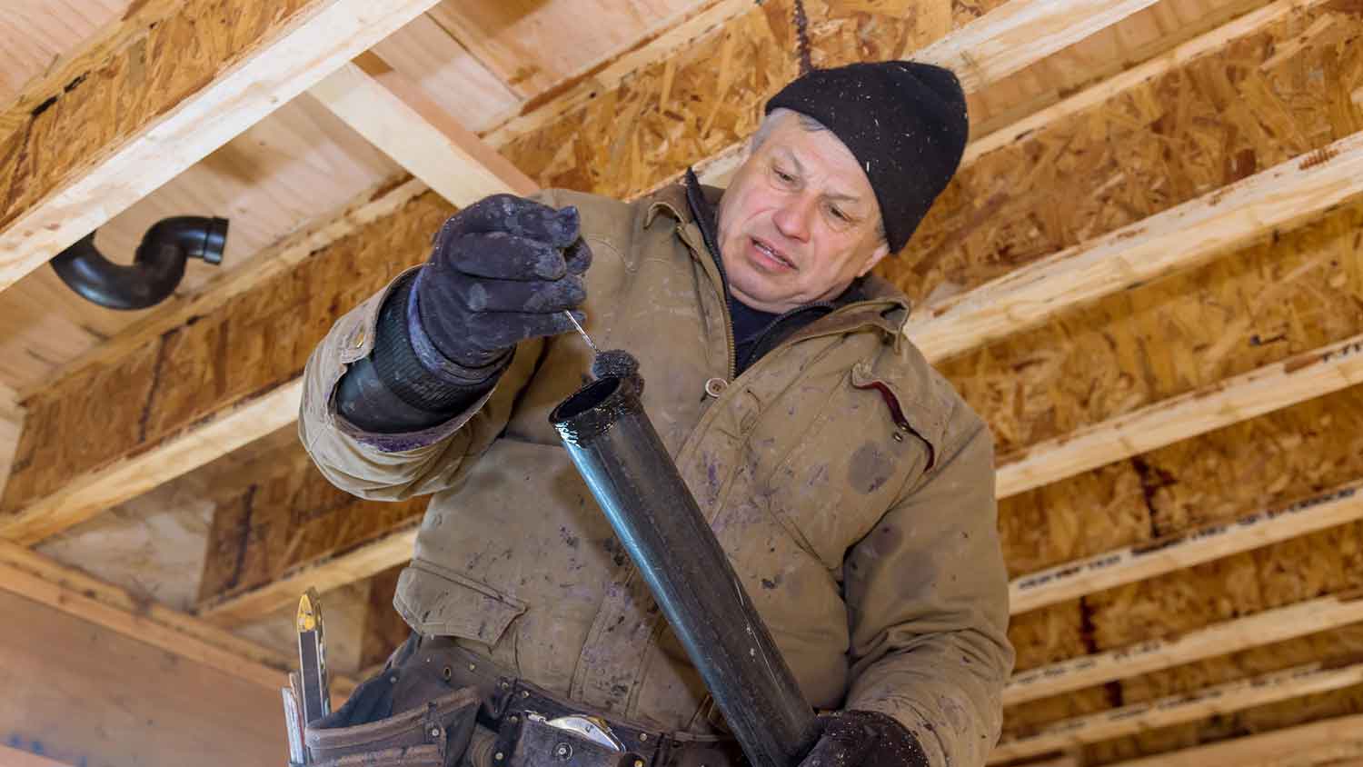 Plumber installing ABS sewer pipe in a new home