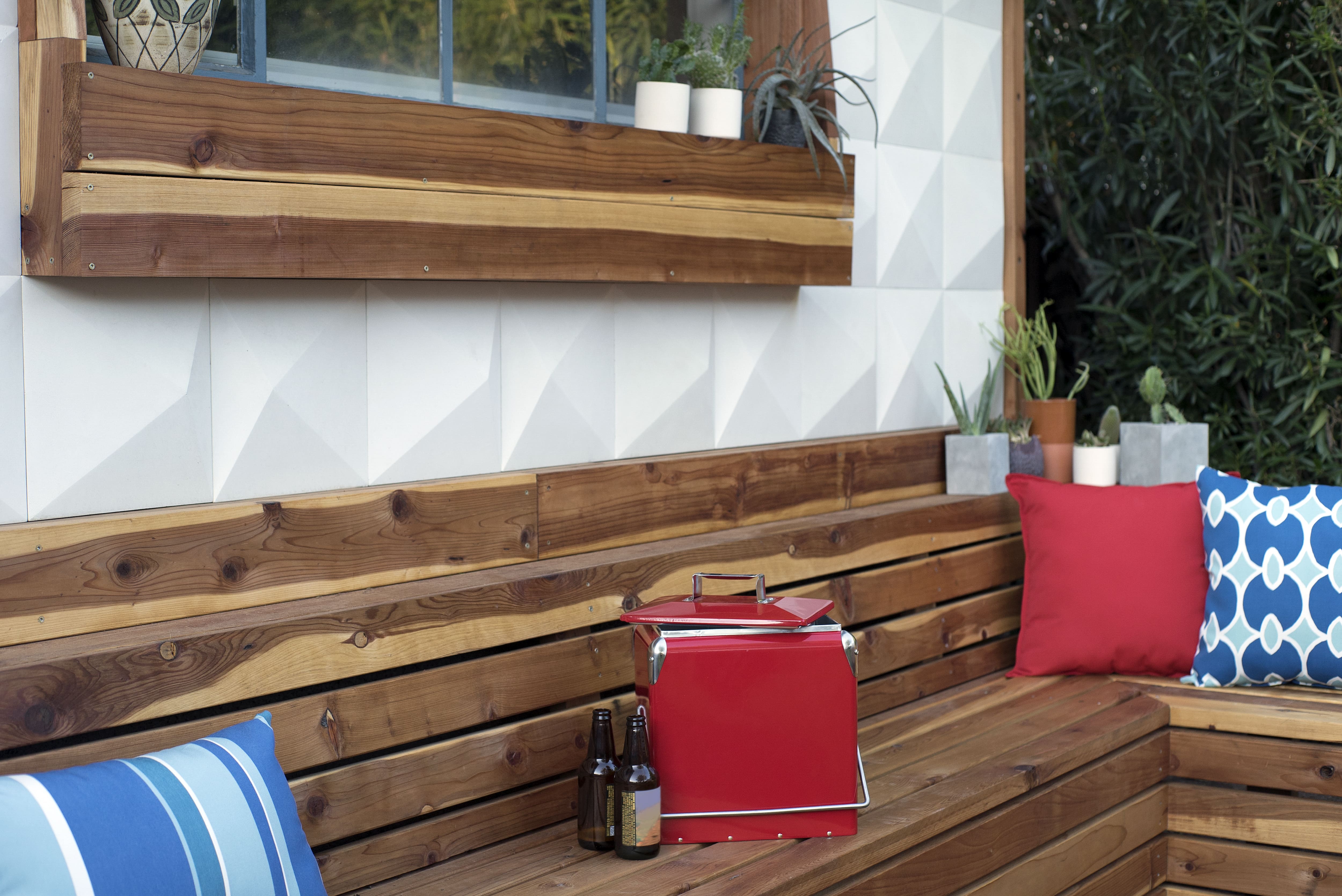 A wooden deck with a built-in sitting bench and cushioning