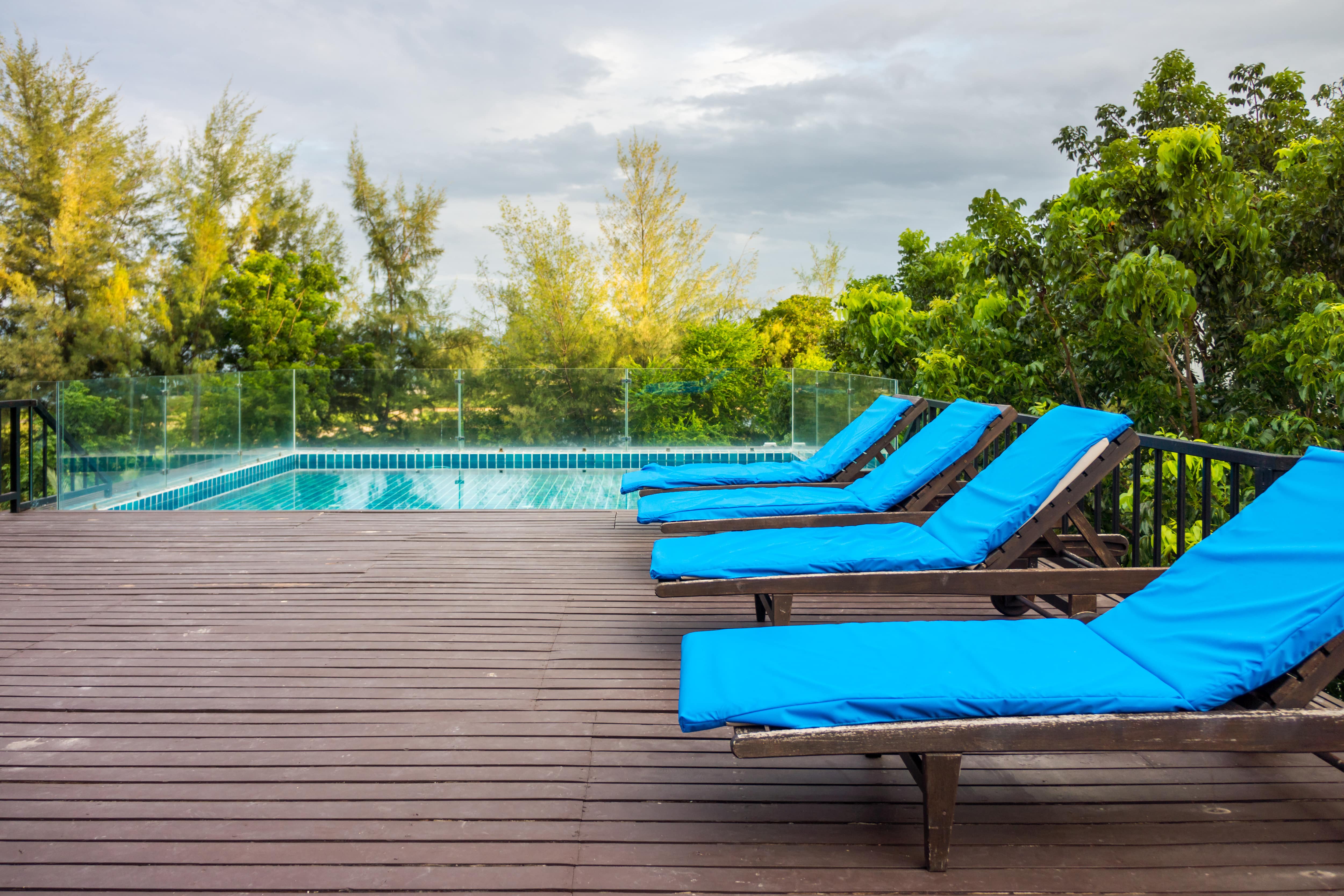 An above-ground pool surrounded by a half deck with four loungers