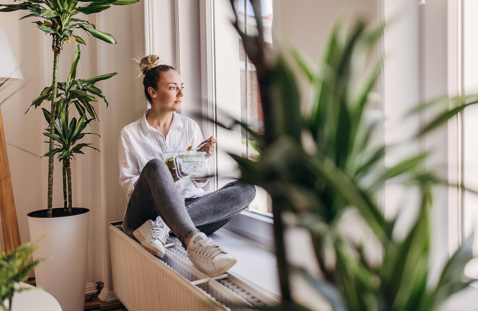 woman sitting by window and eating