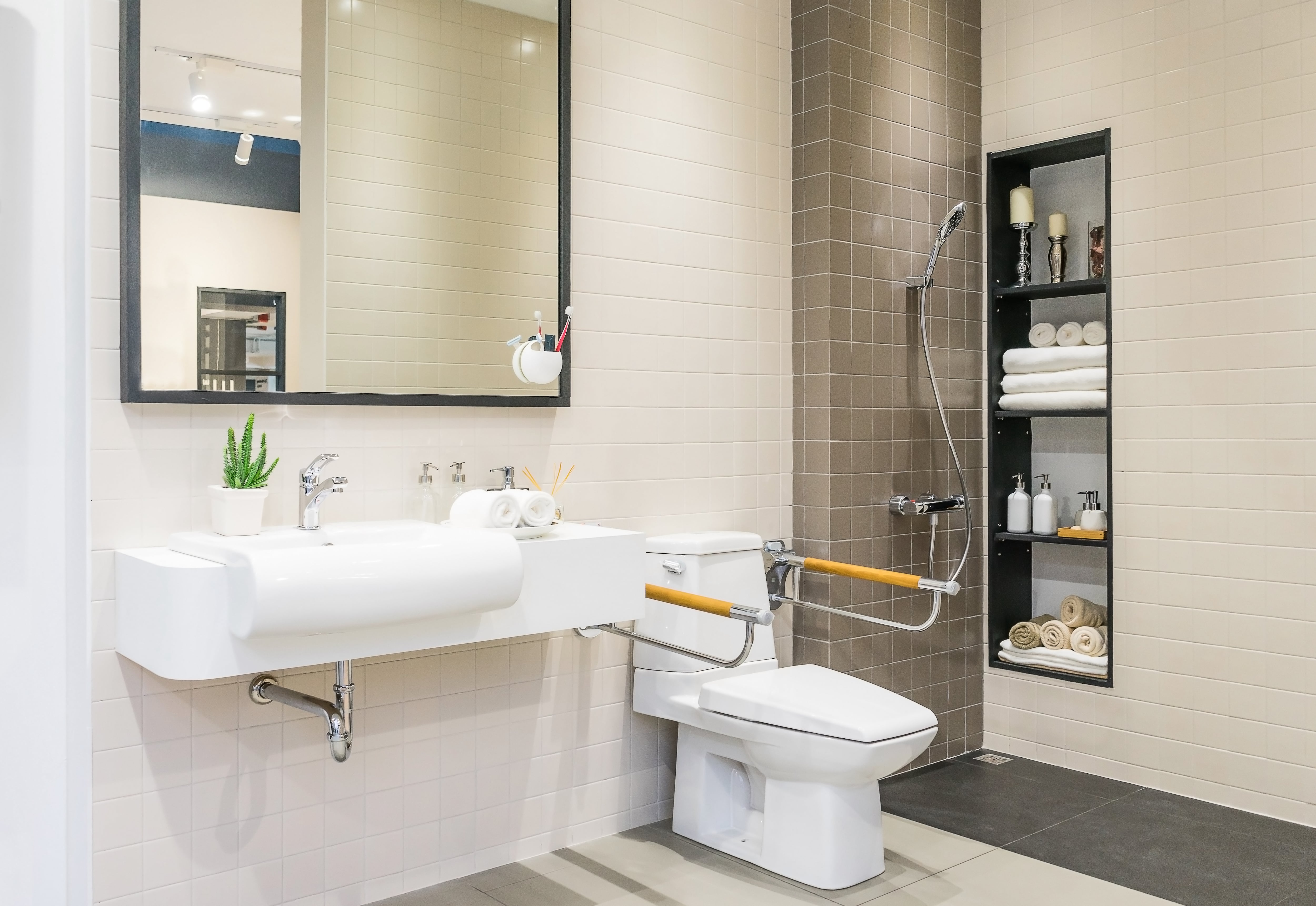 ​​Accessible home bathroom with curbless shower and toilet handrail for people with disabilities