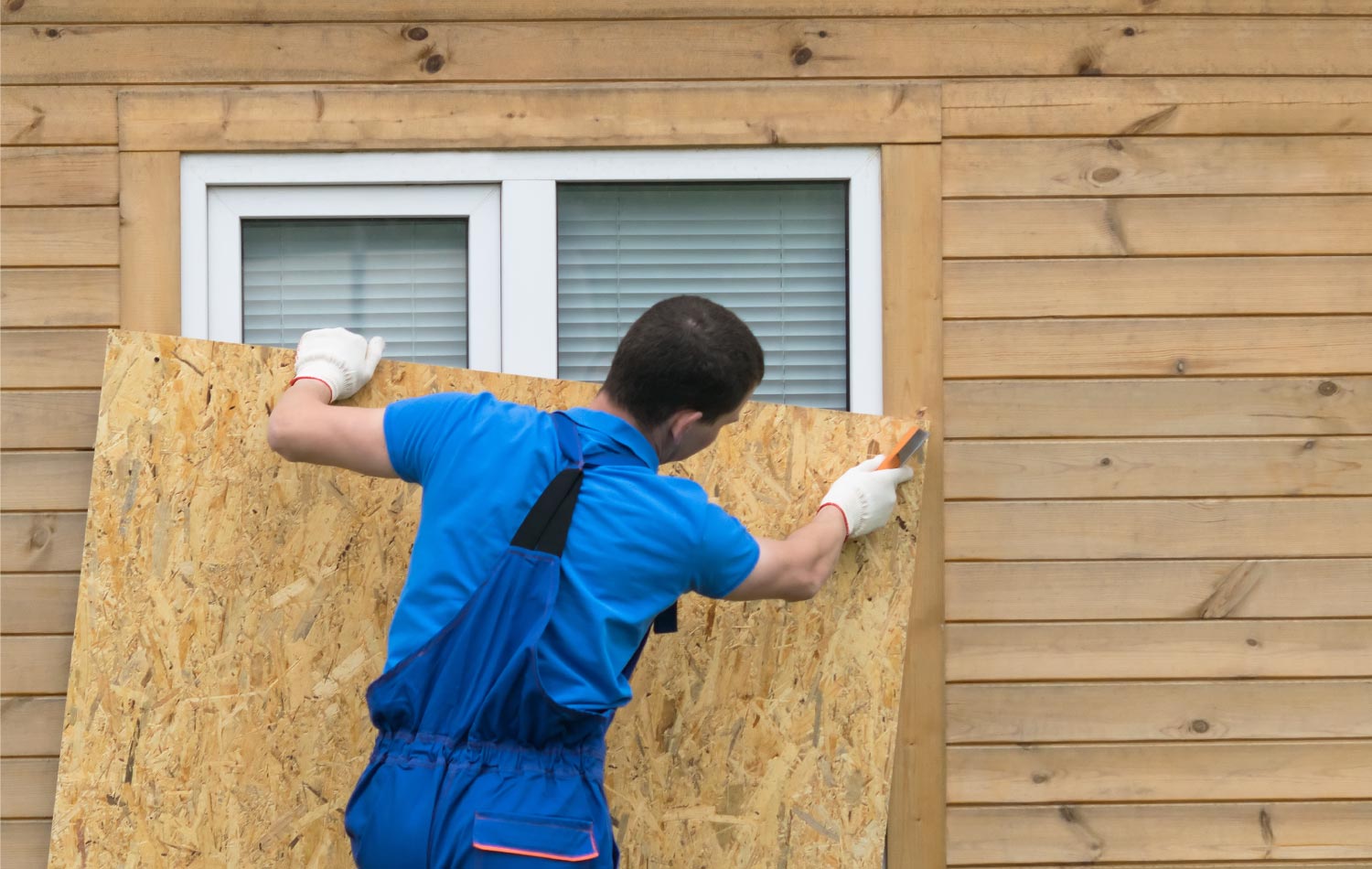 A man installing boards to protect the window