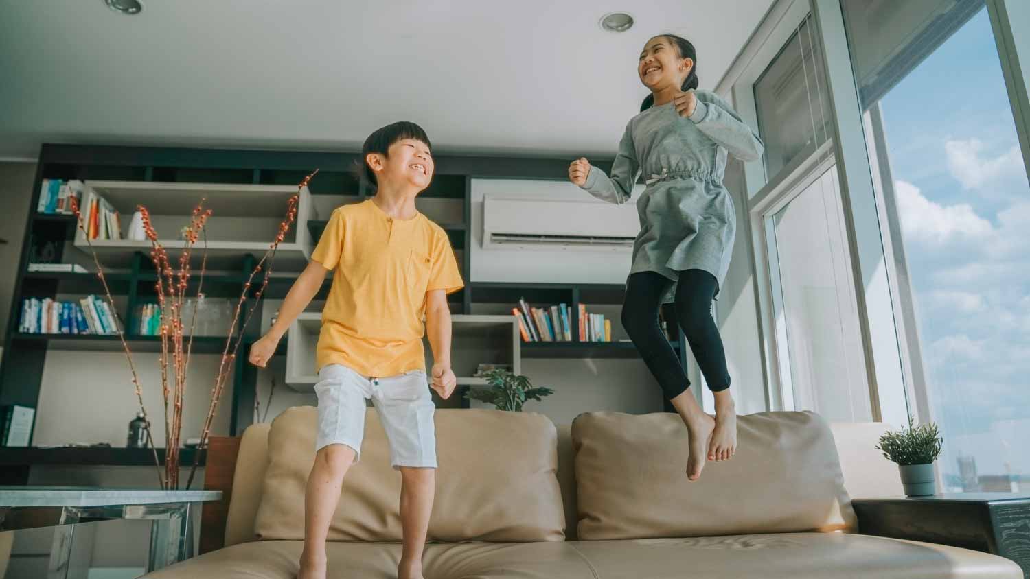 Boy and girl jumping on the couch sofa
