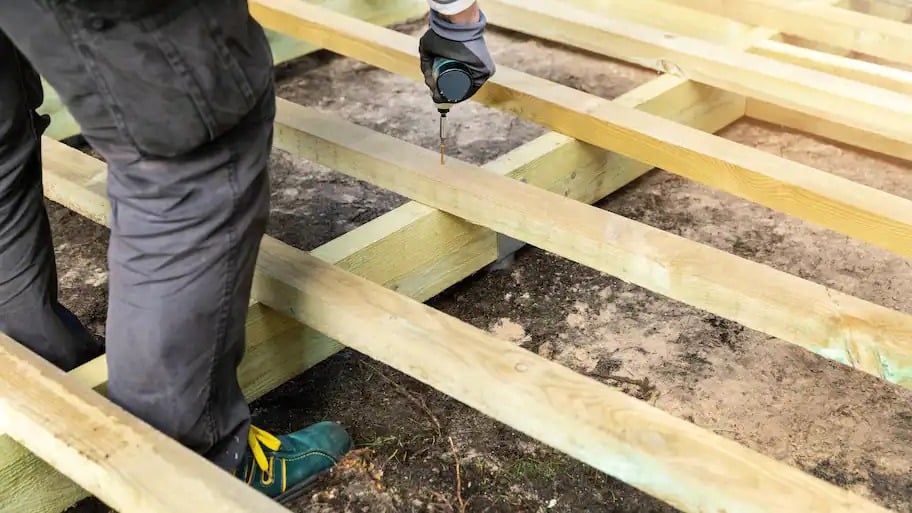 A construction worker building the floor frame of a structure