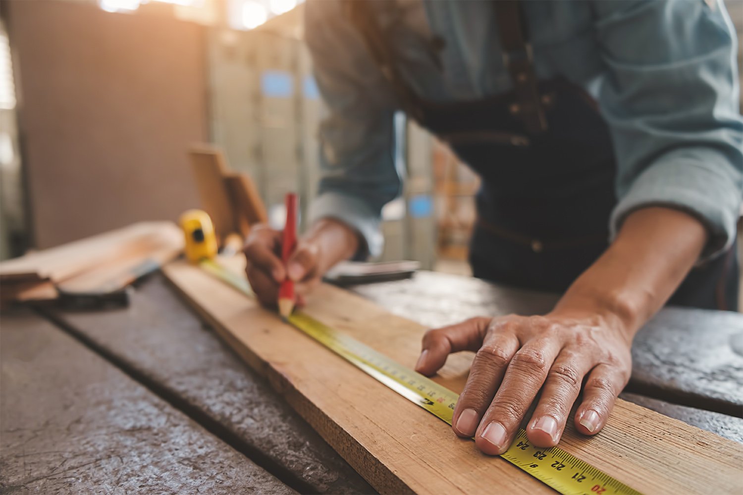 Carpenter using measuring tape to mark lumber