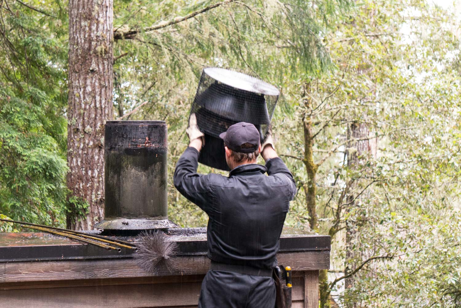 Chimney sweep cleaning on roof of a house