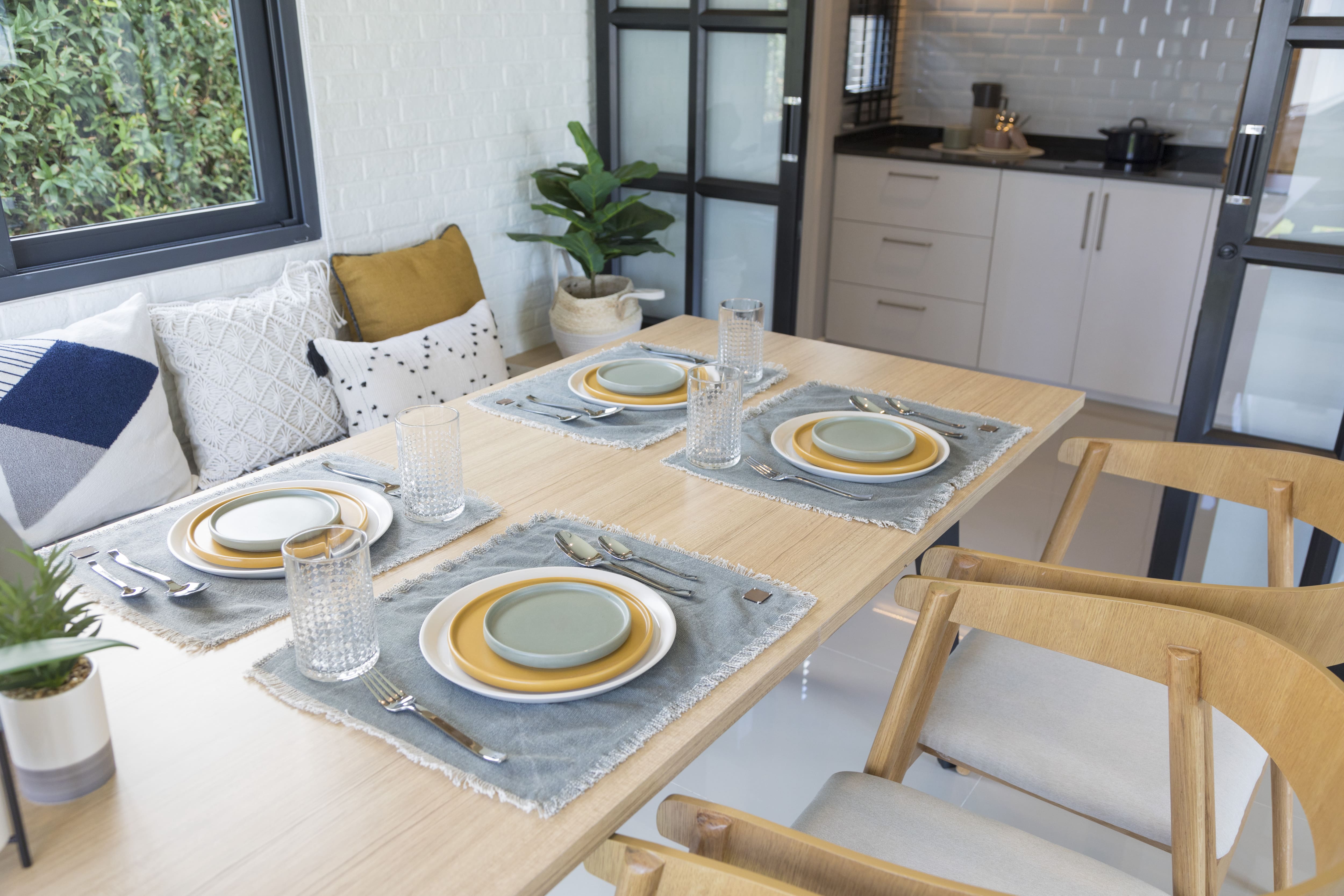 Dining table with stacked yellow, sea foam, and white plates on top of cotton placemats 