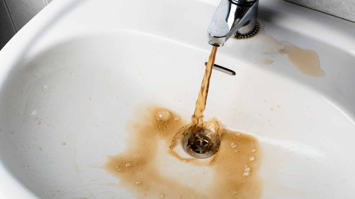 Dirty brown water running into a sink