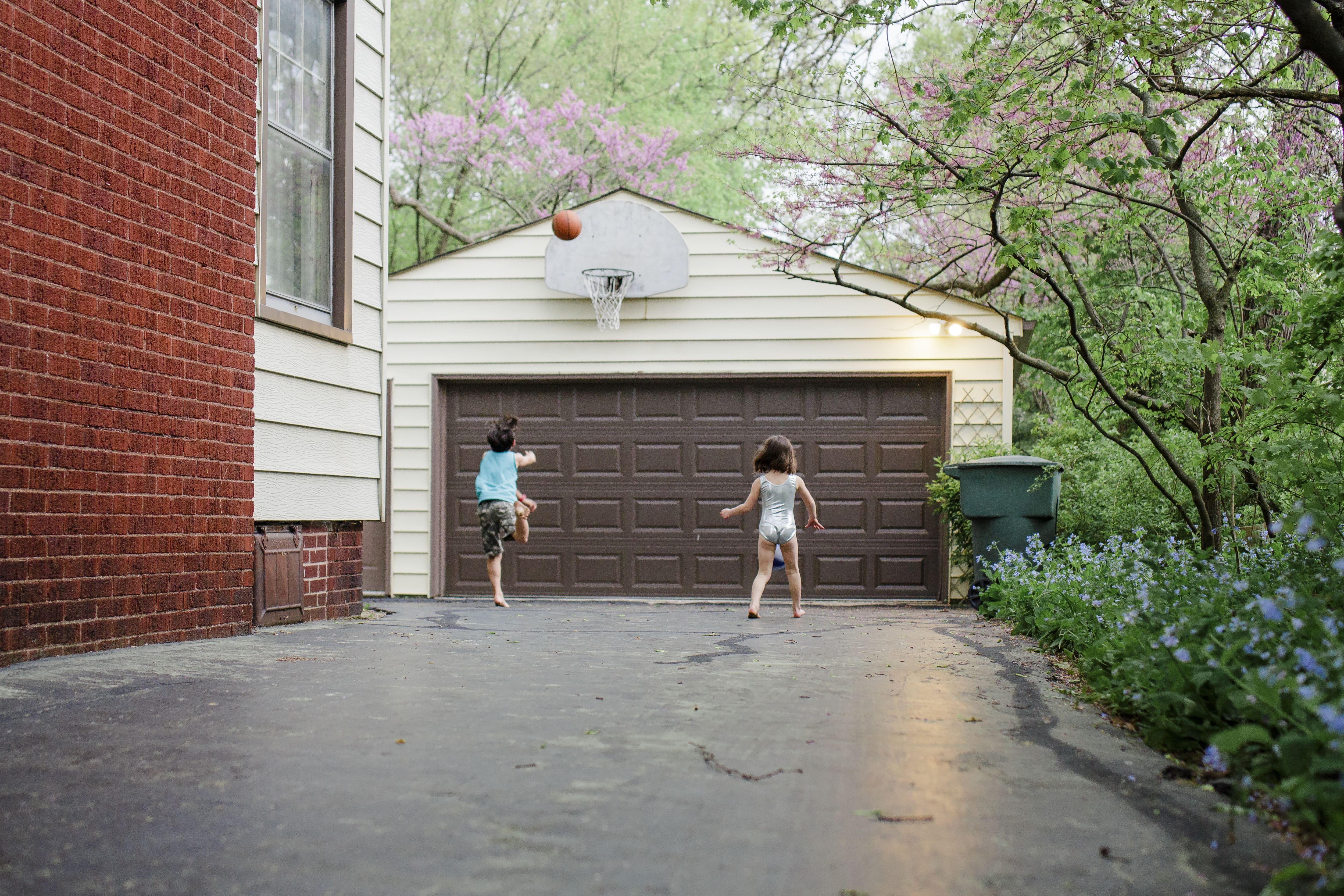 Kids playing basketball on asphalt driveway