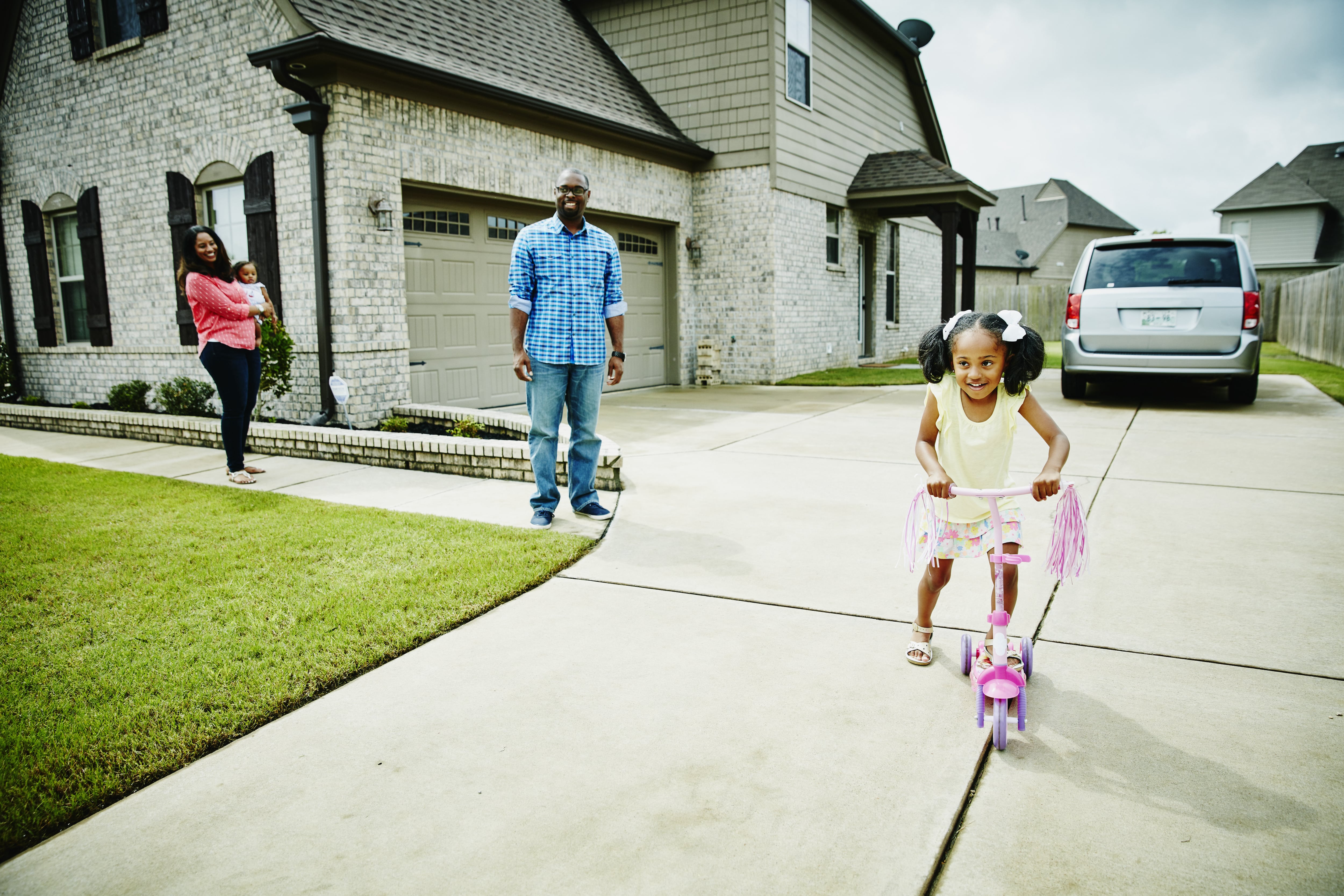 Girl riding scooter on concrete driveway