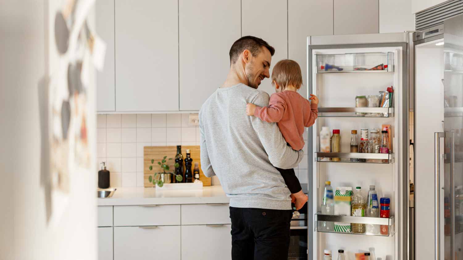 Father carrying toddler daughter in kitchen