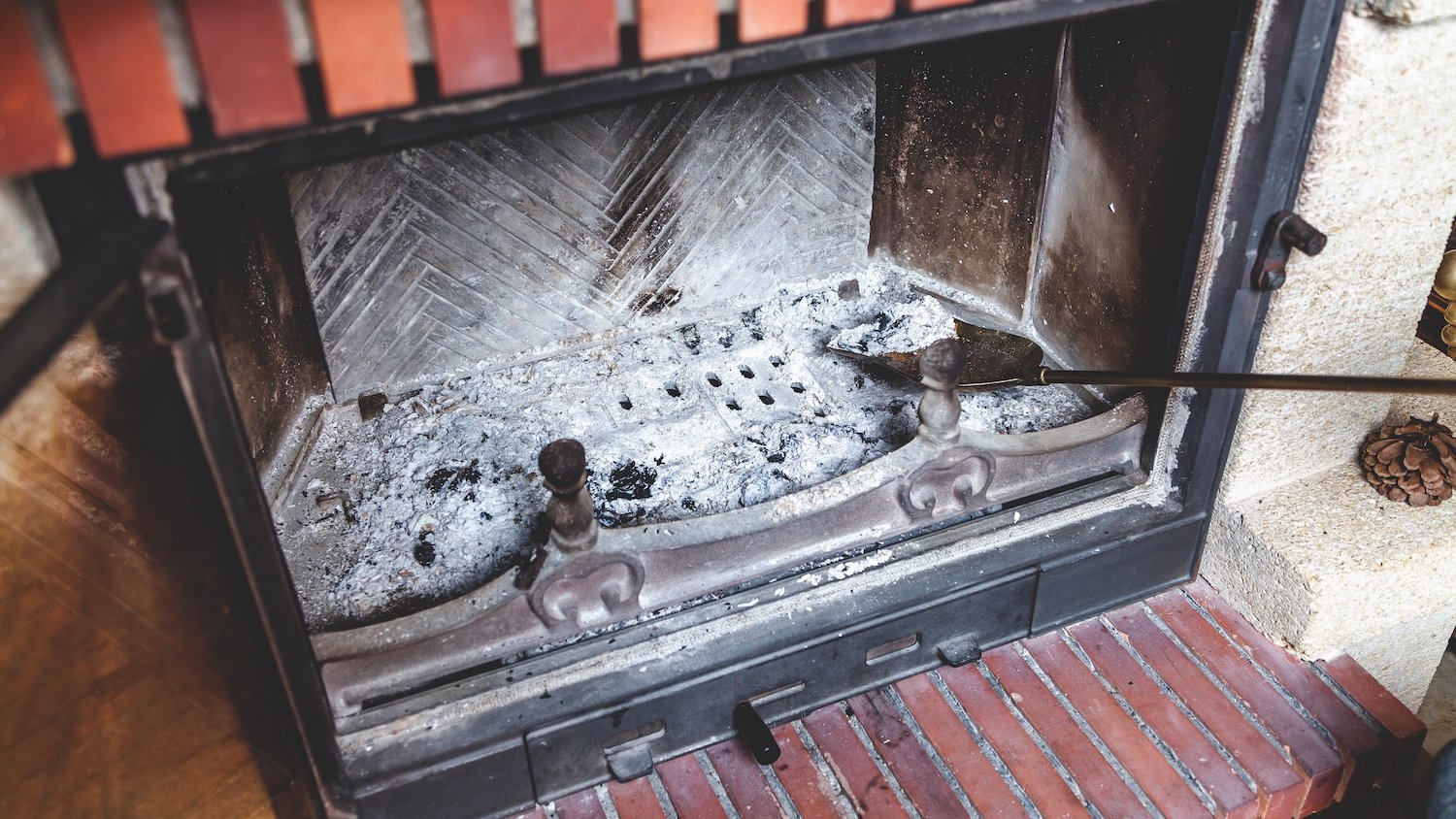 A small shovel being used to pick up debris from a fireplace