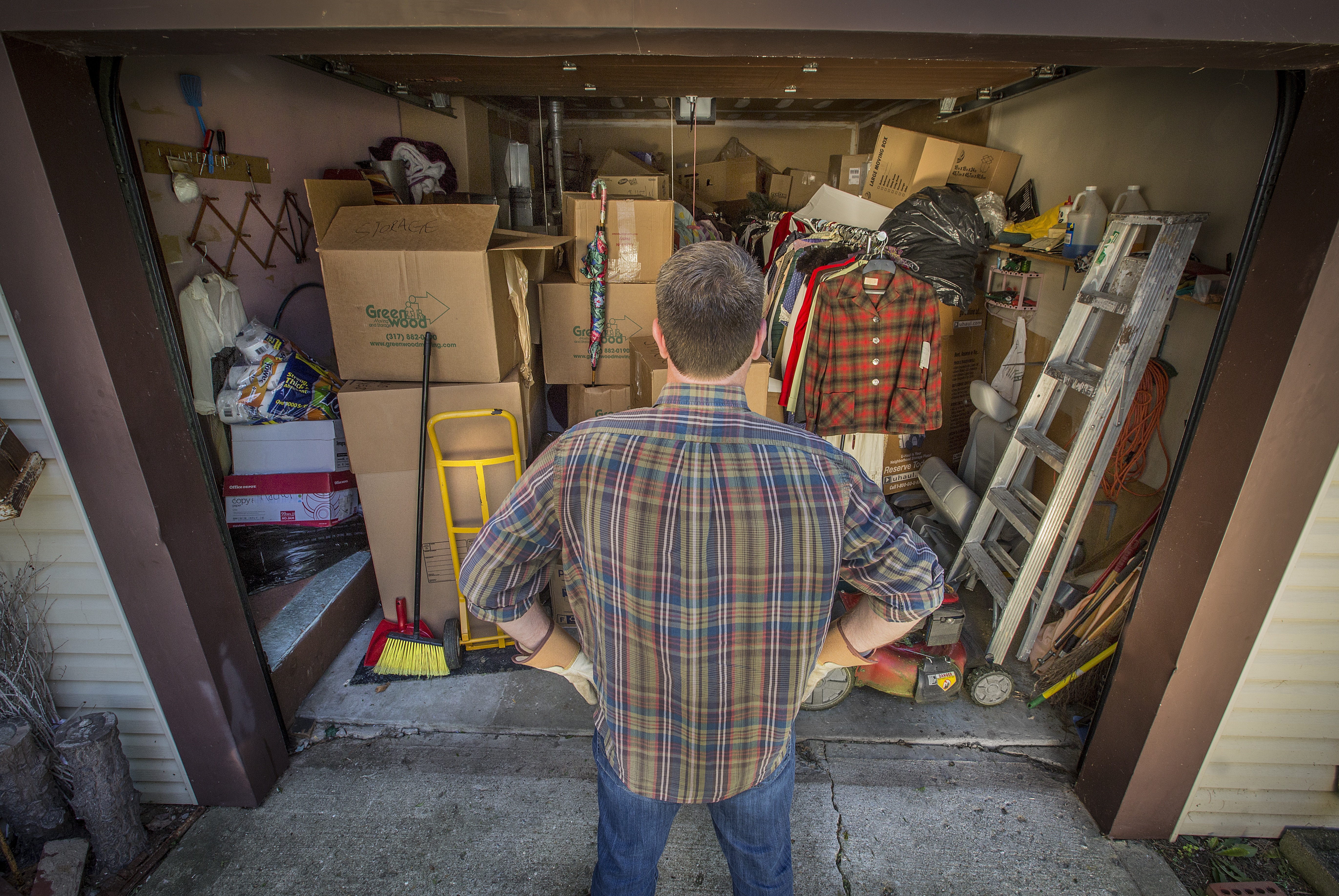 Guy staring into garage packed with boxes and other items.