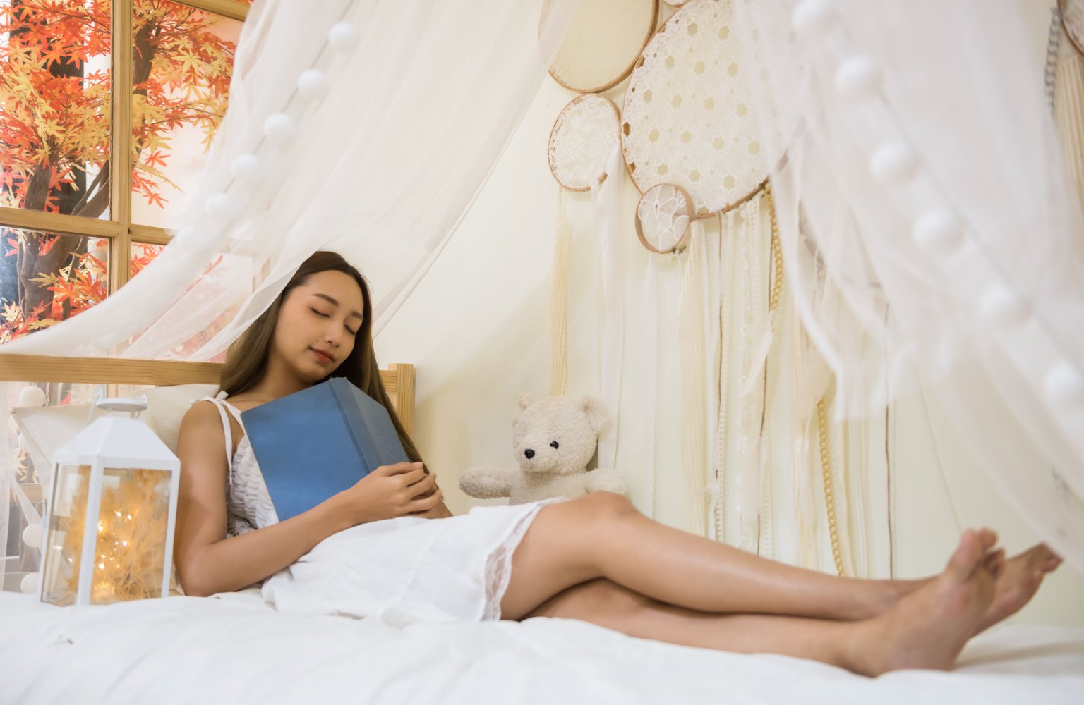 girl taking a nap in bedroom with book on lap