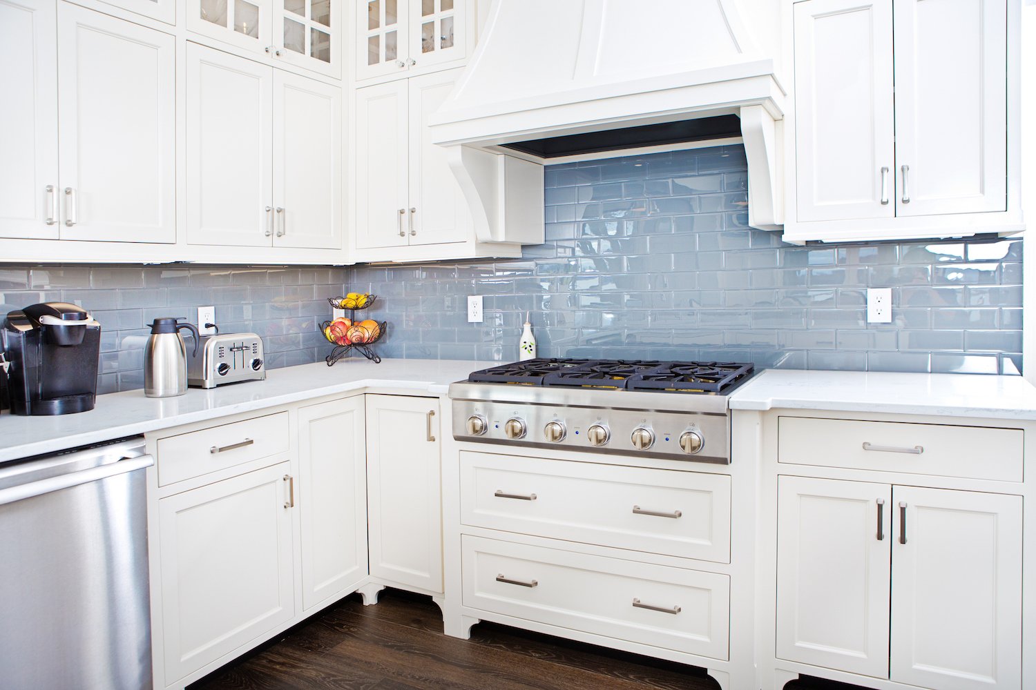 Kitchen with blue-gray iridescent tile backsplash and white cabinets