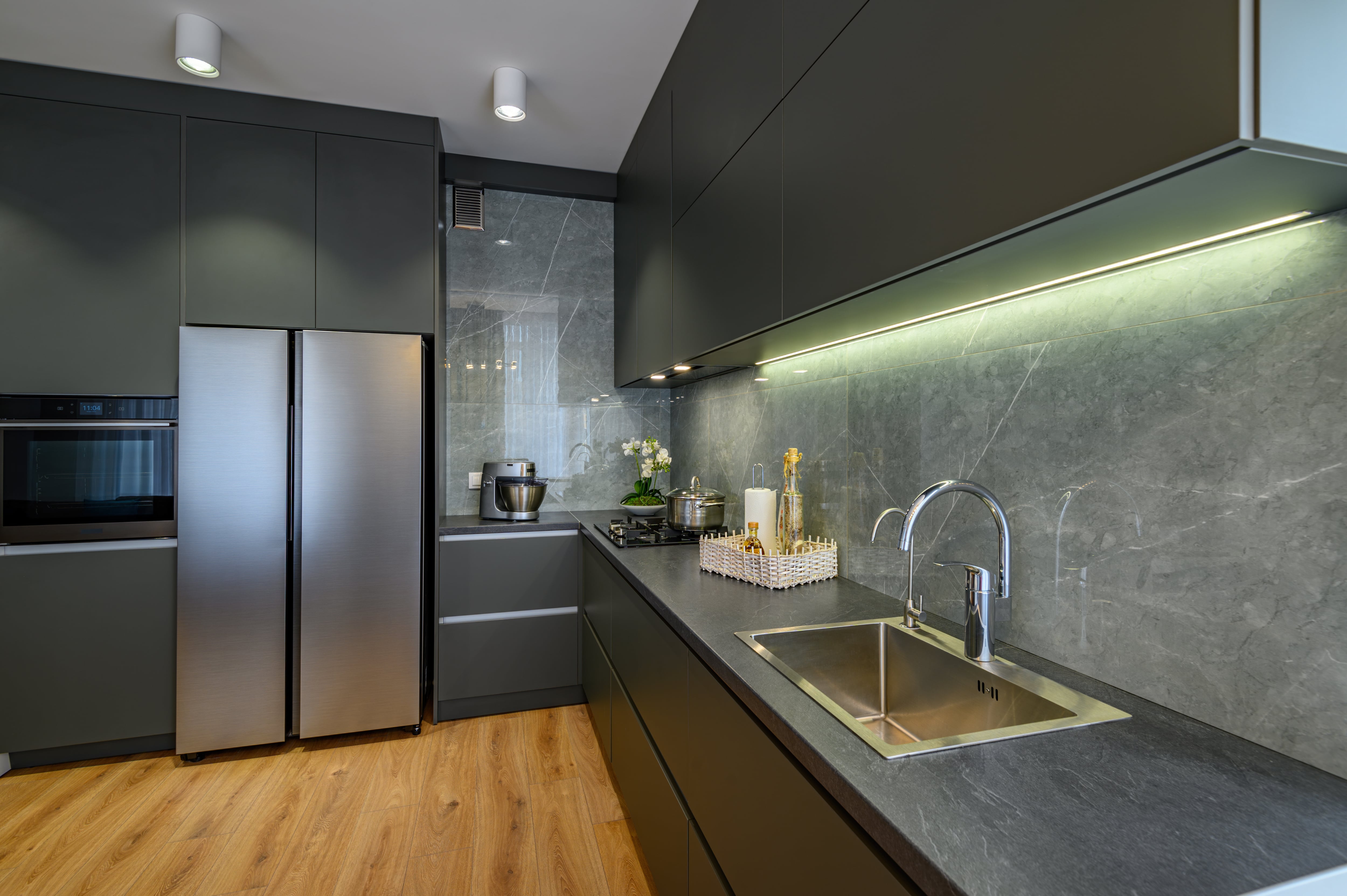 Modern luxury kitchen with gray soapstone countertops and backsplash, gray cabinets, and stainless appliances
