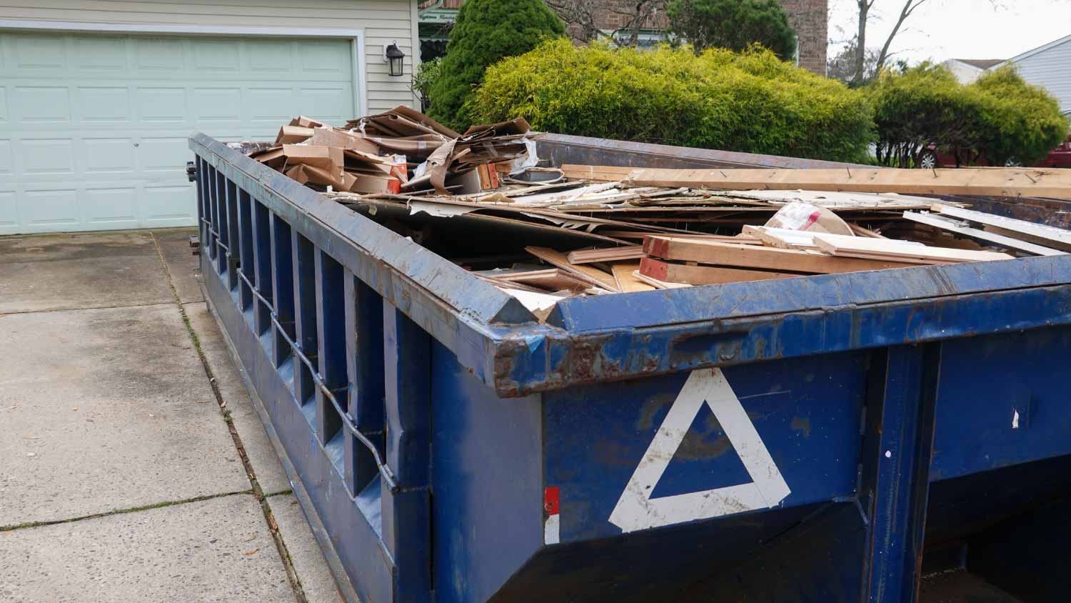 Long blue dumpster full of wood