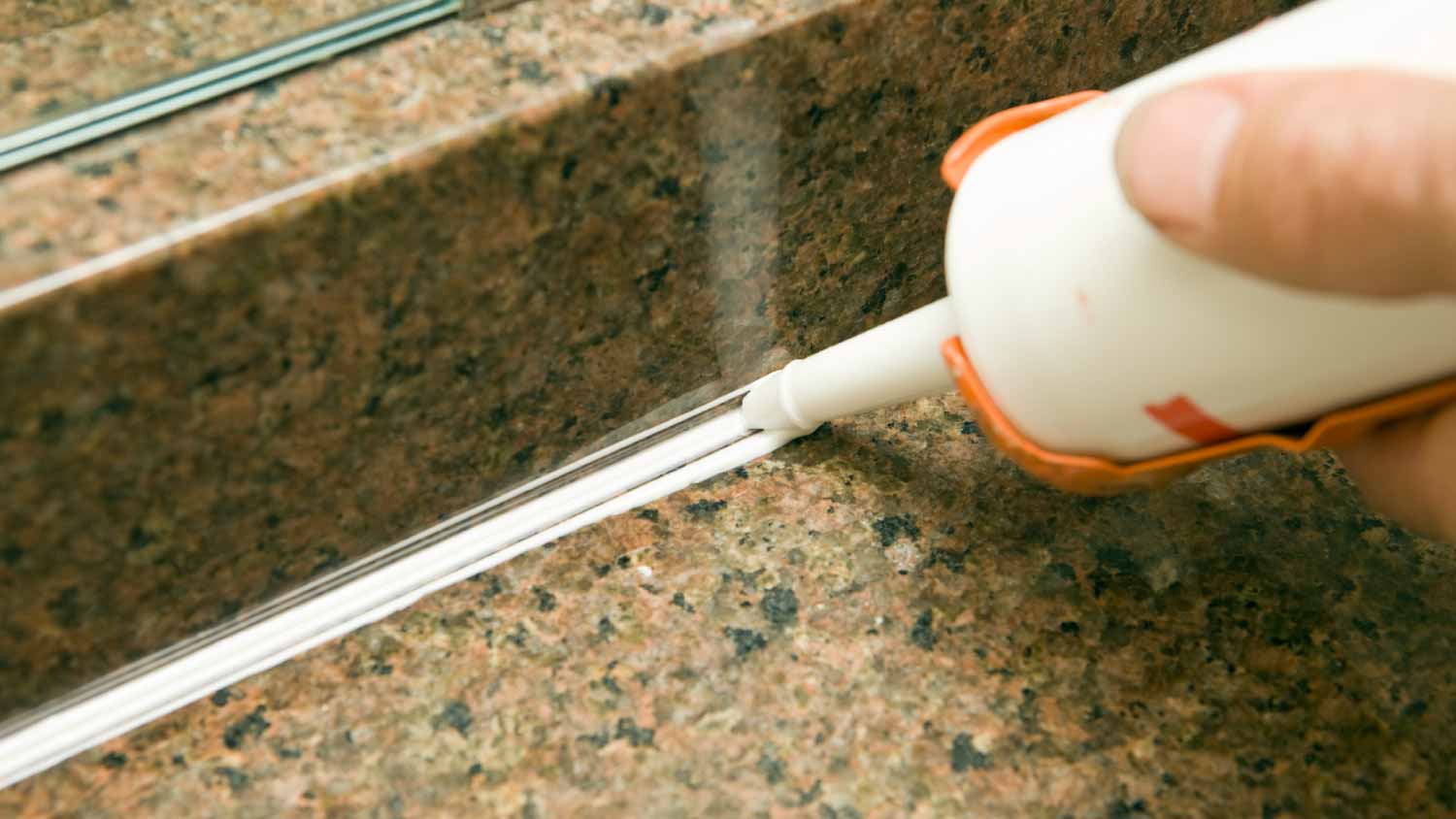 Man applying silicone to granite