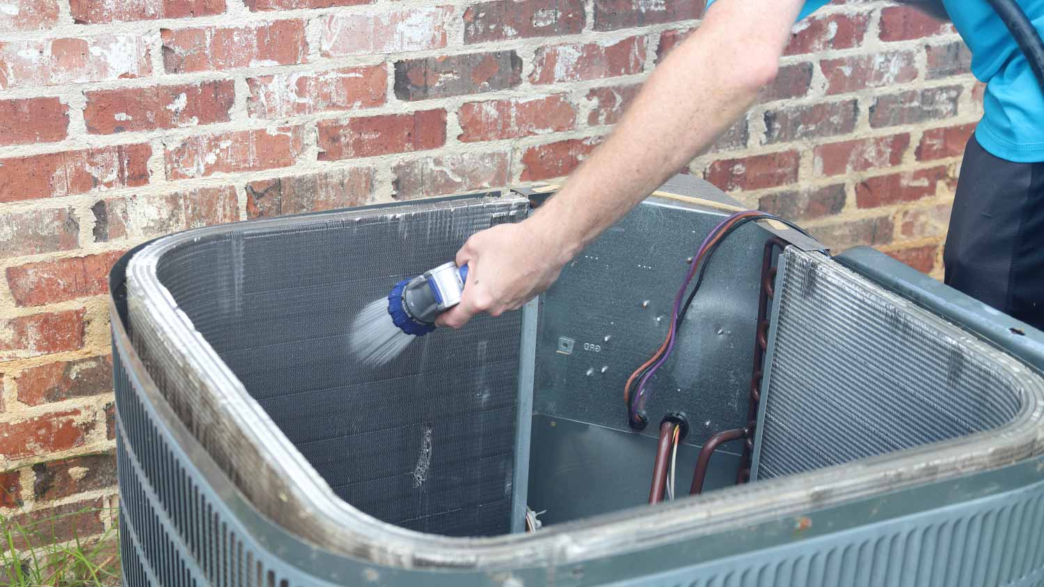 Man cleaning air conditioner condenser coils