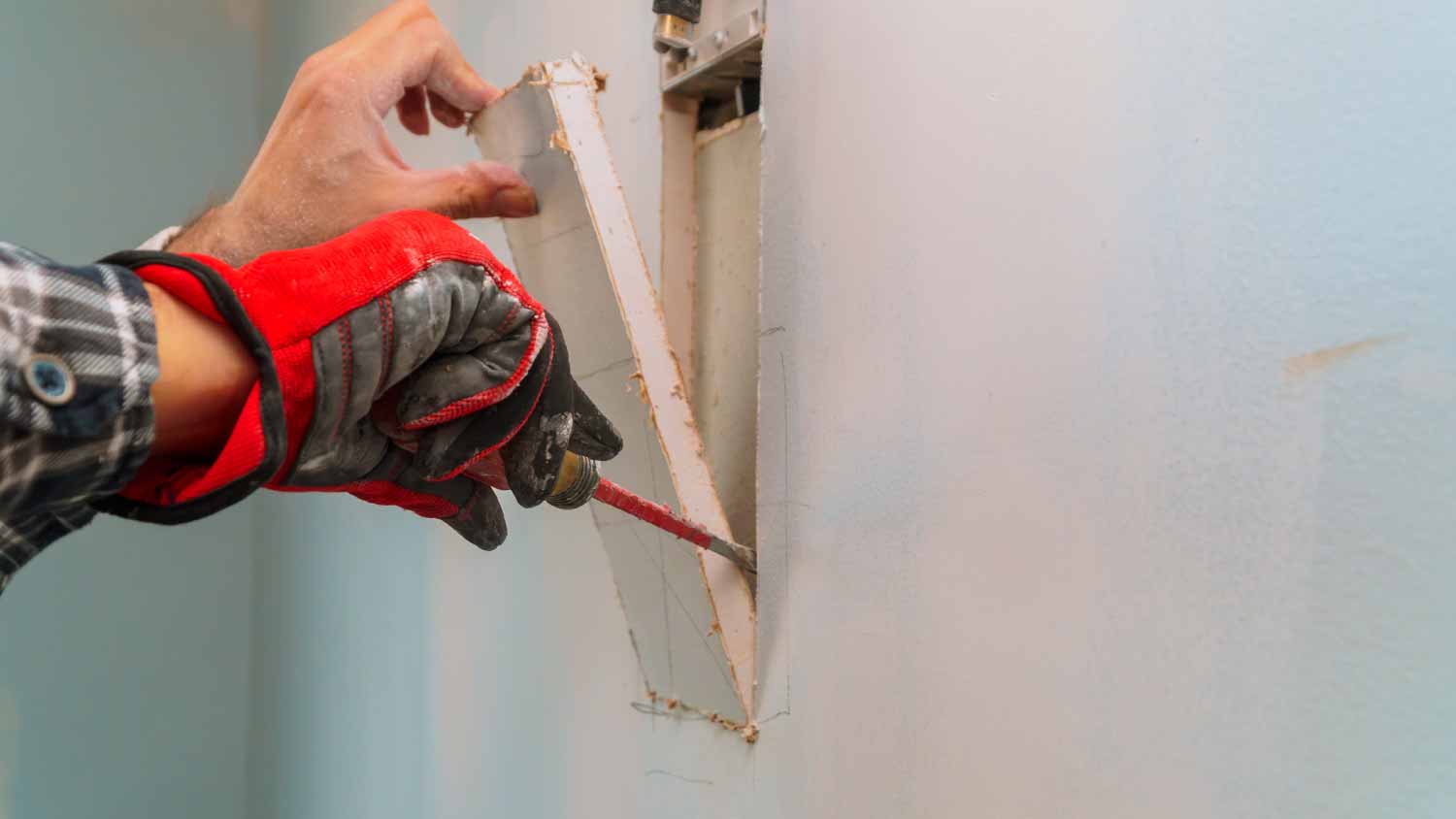 Man cutting a hole in the drywall