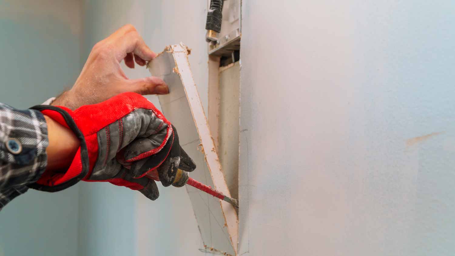 Man cutting a hole in the wall