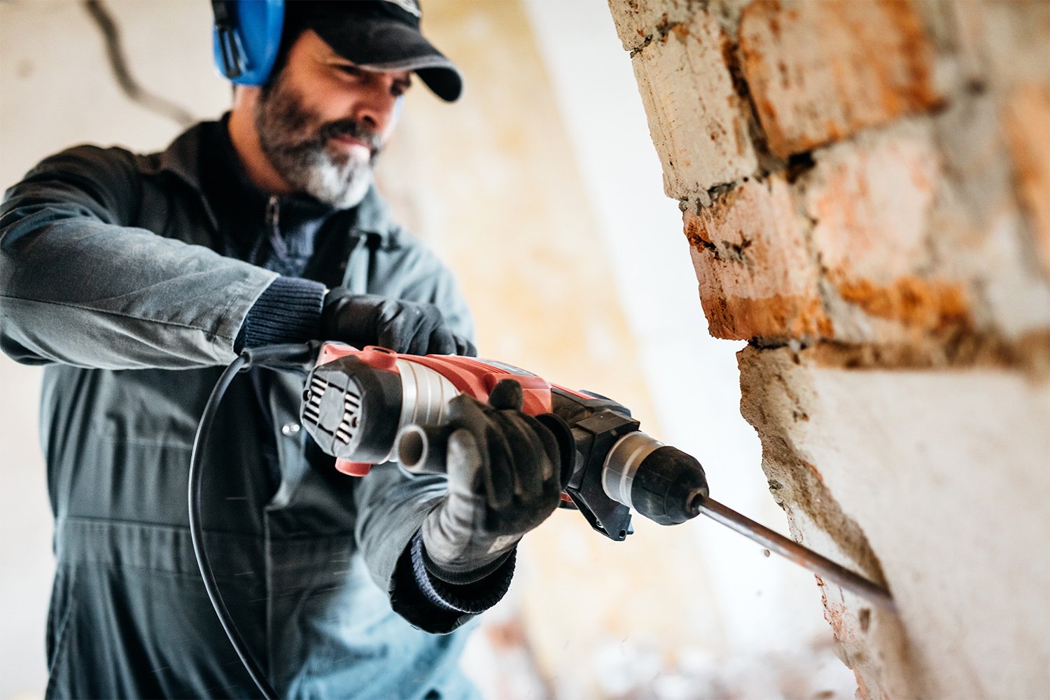 Professional knocking down a wall by using a drill