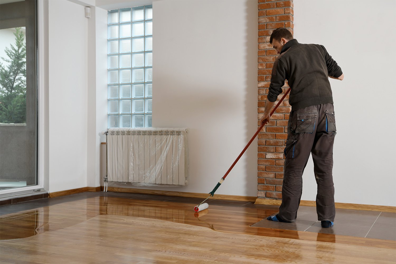 Man adding gloss finish to wood floor