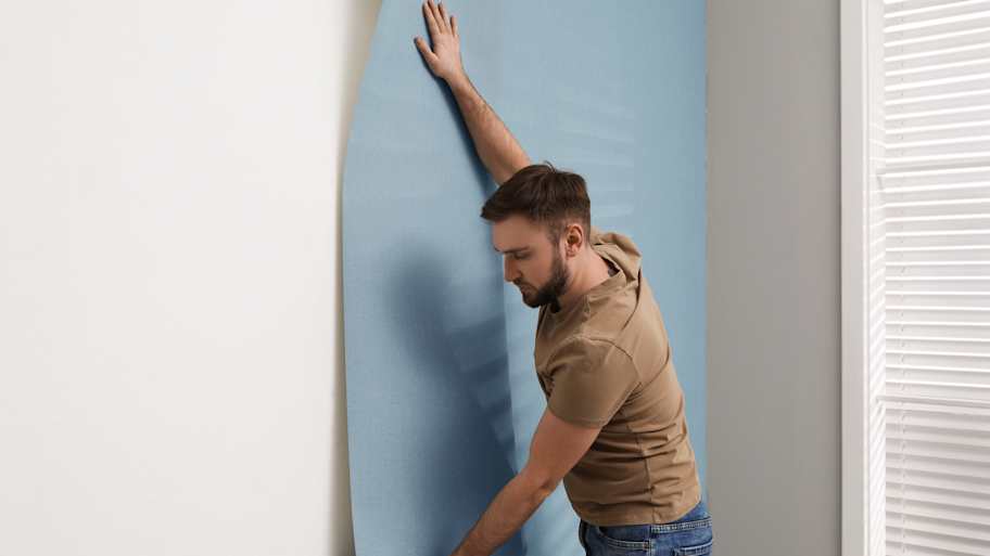 Man hanging stylish wallpaper