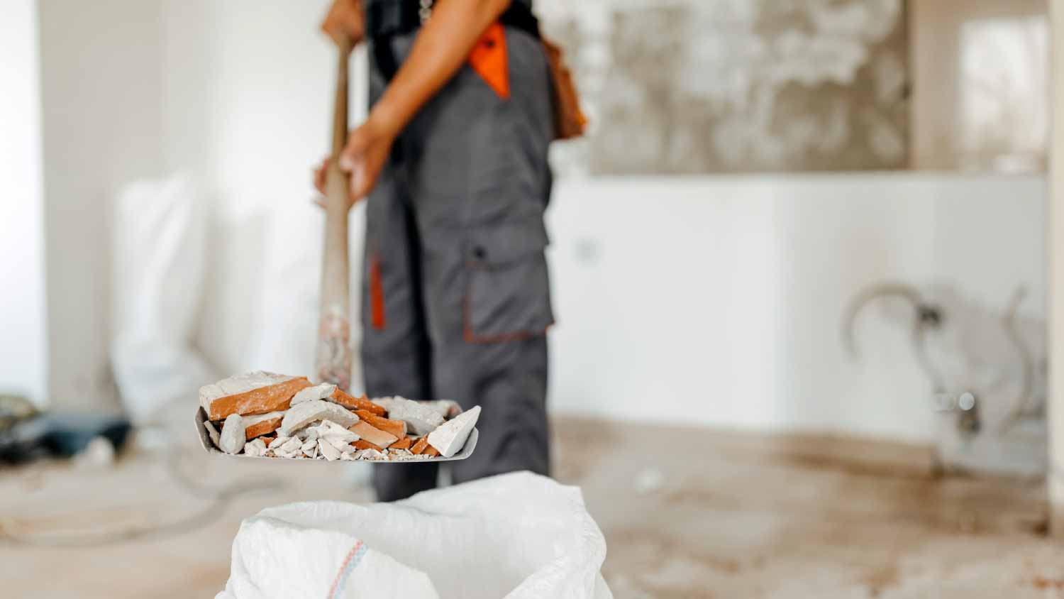 Man holding a shovel filled with construction residue