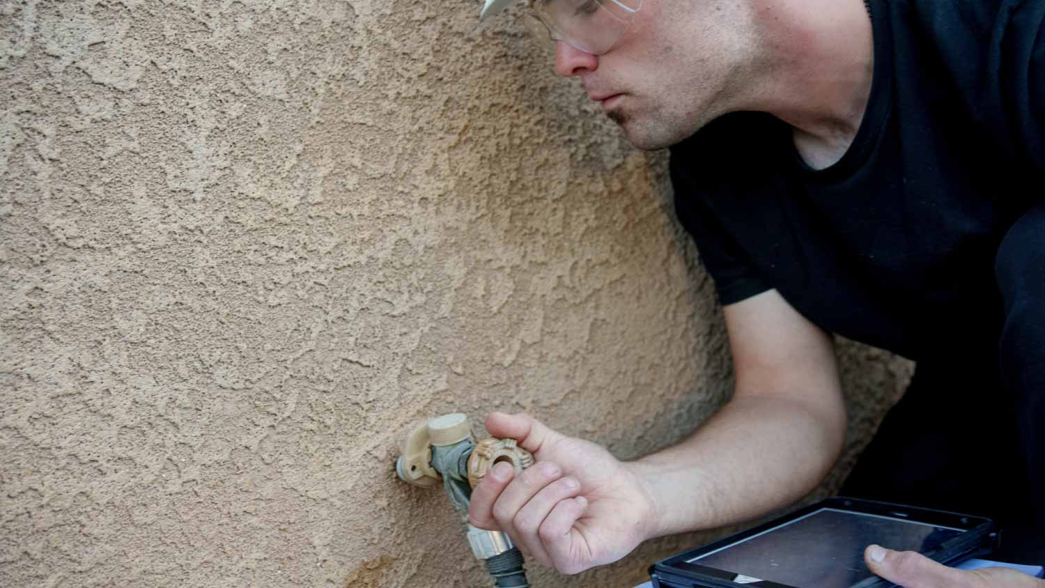 Man inspecting outdoor water faucet