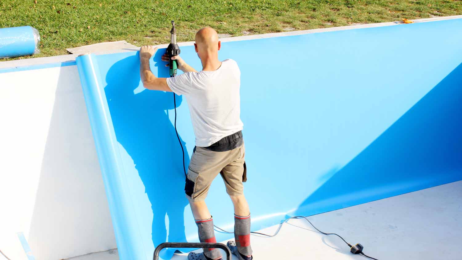 Man installing plastic cover for water pool