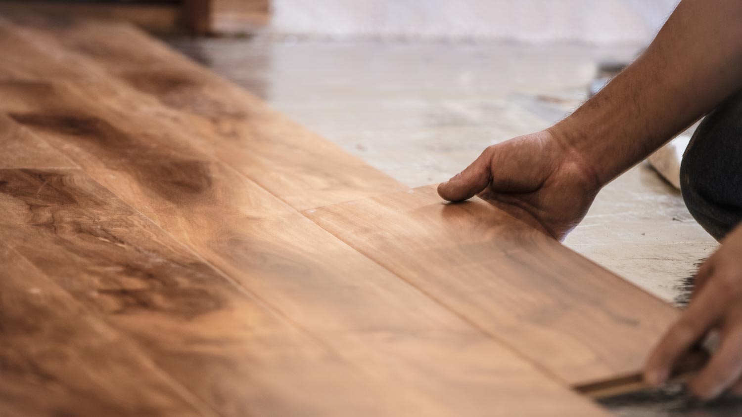 A man installing wood flooring in home